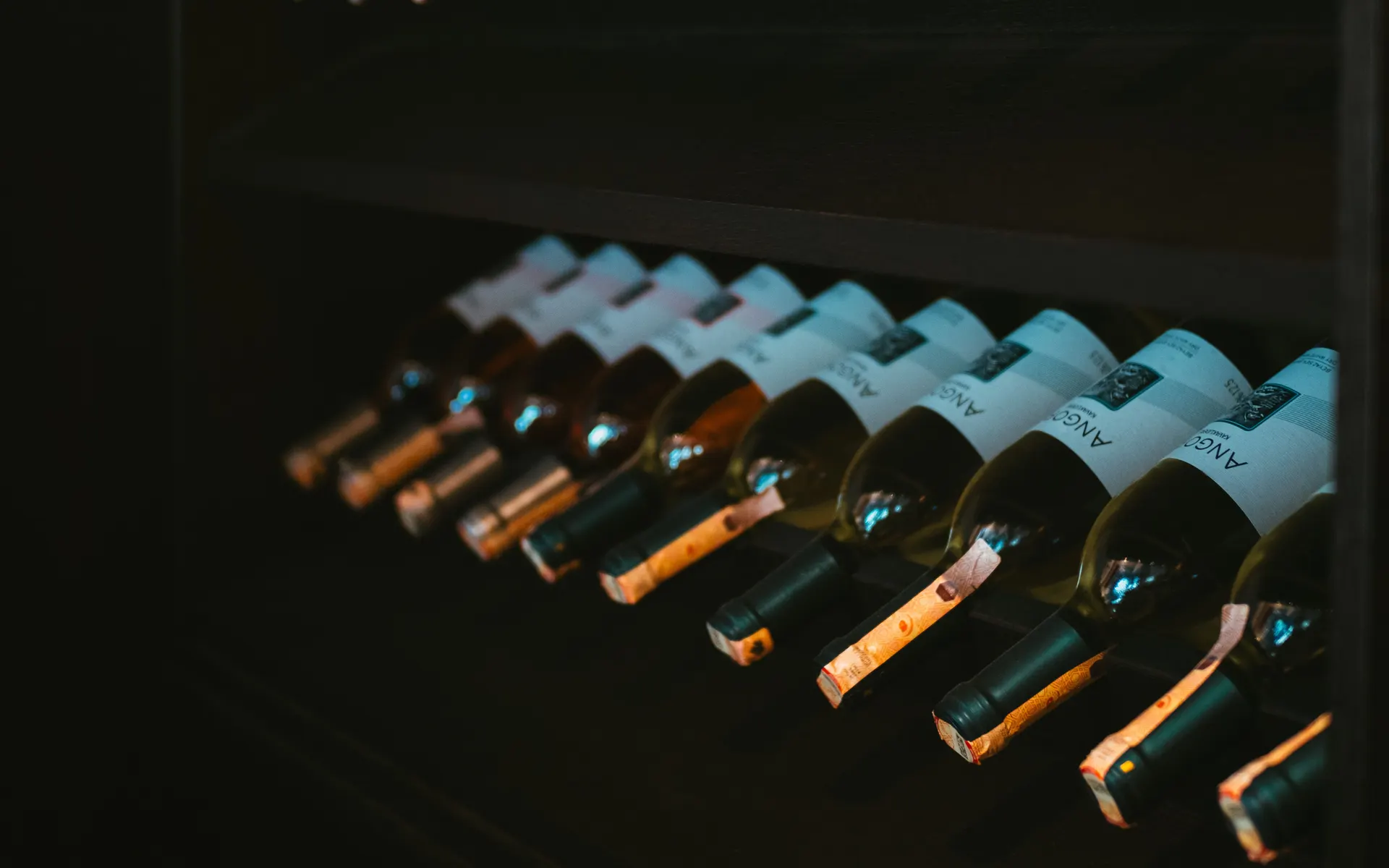 Rows of wine and spirits bottles resting in a climate-controlled Napa Valley cellar rack